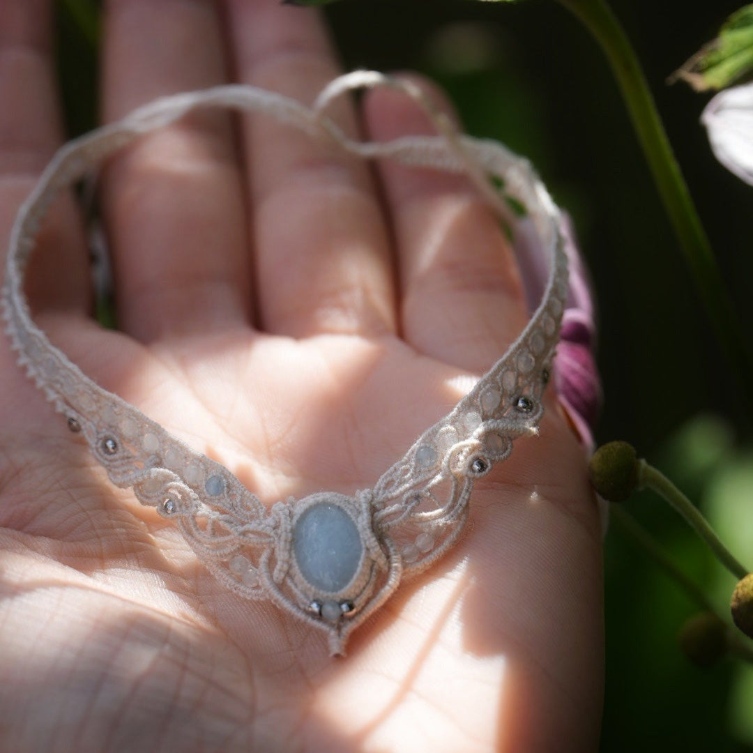 Bijou de cheville en micro macramé écru et aigue-marine posé sur une peau claire, bracelet mariage elfique et sirène. Coton et Astrance