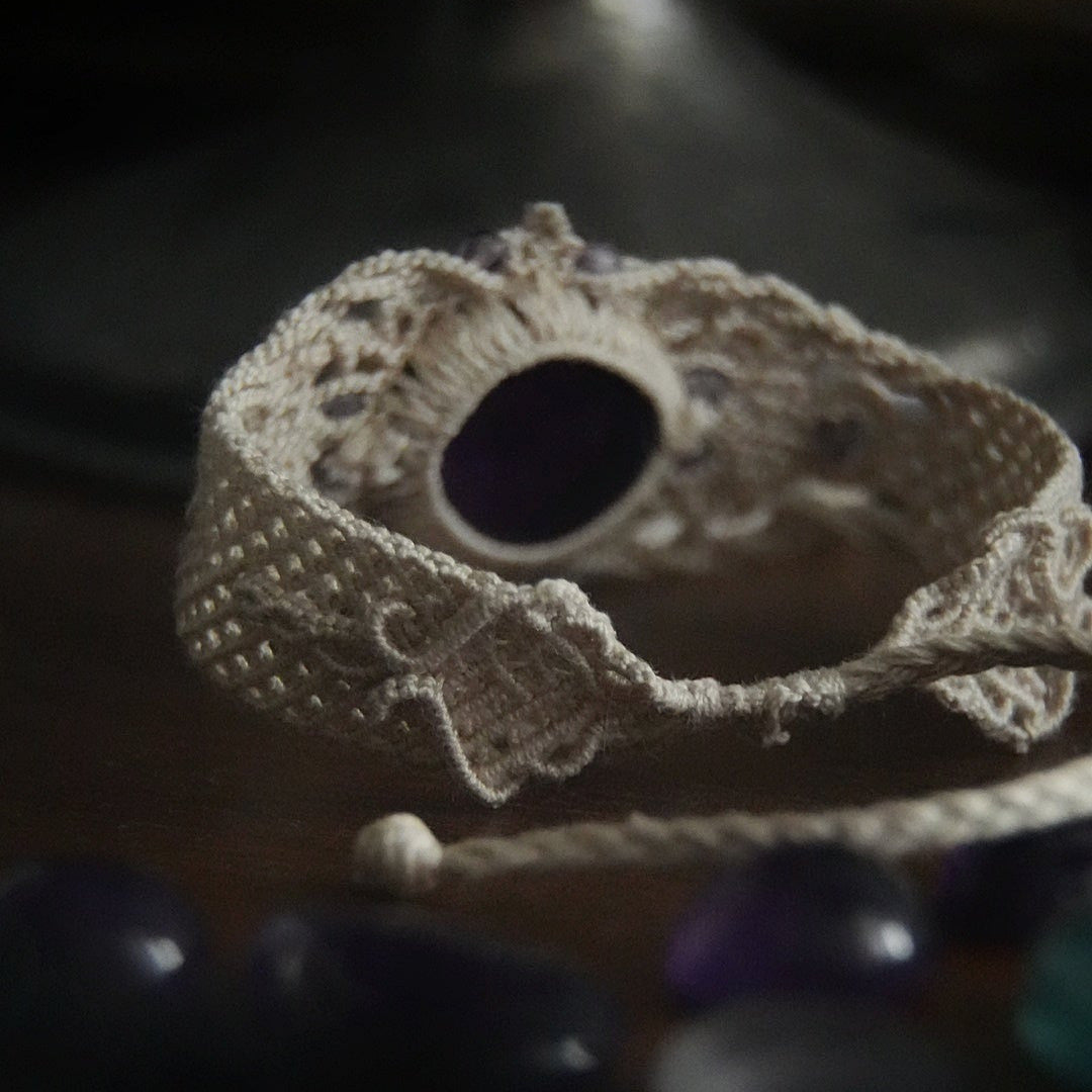 Bracelet large en macramé avec améthyste naturelle, bijou artisanal spirituel photographié dans un univers wicca gothique. Coton et Astrance