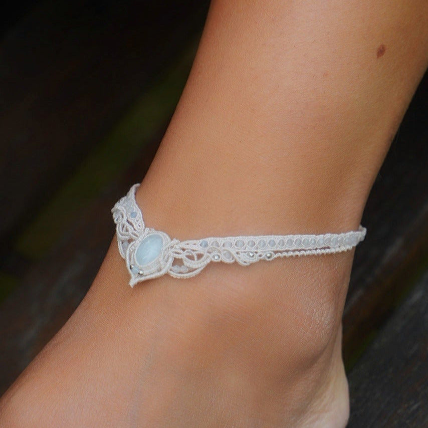Bracelet de cheville elfique en aigue-marine porté sur une mariée pieds nus, bijou bohème sirène en coton écru réglable. Coton et Astrance