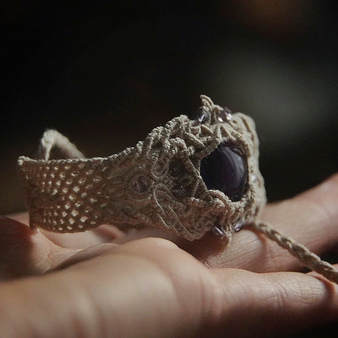 Bracelet large en macramé avec améthyste naturelle, bijou artisanal spirituel photographié dans un univers wicca gothique. Coton et Astrance
