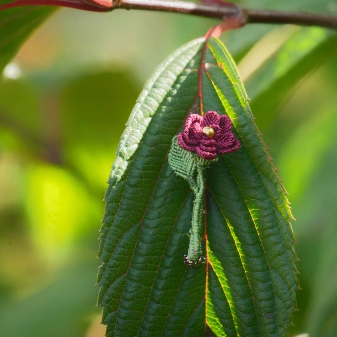 Broche florale rouge en micro macramé avec cœur doré, accrochée à une feuille, bijou elfique et bohème fait main, inspiré de la nature et des fleurs sauvages.