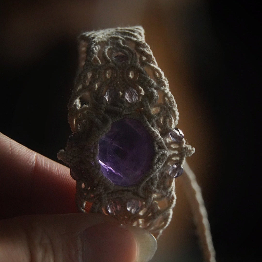 Bracelet manchette en améthyste violette, bijou wicca artisanal en micro macramé, porté avec dentelle noire dans une ambiance sorcière mystique. Coton et Astrance