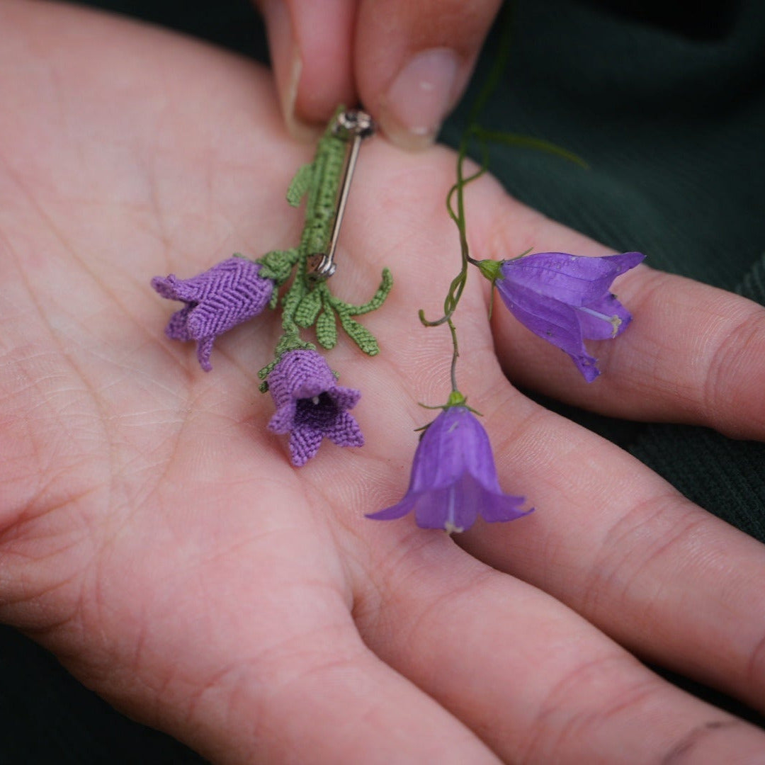 Bijou unisexe en micro macramé. Accessoire de mode inspiré de la nature et des fleurs sauvages d'été. Broche composée de deux campanules violettes avec feuille ciselée. Support de broche en laiton rhodié argenté fin avec cliquet de sécurité à tourner. Accessoire elfique, féérique pour veste, sac ou chapeau. Parfait en Boutonnière de mariage pour homme ou comme accessoires bohème pour costume et tenue de Festival. Bijou d'été poétique en 3D. Réalisé avec fil de coton de 0,3 mm vert tendre et violet.