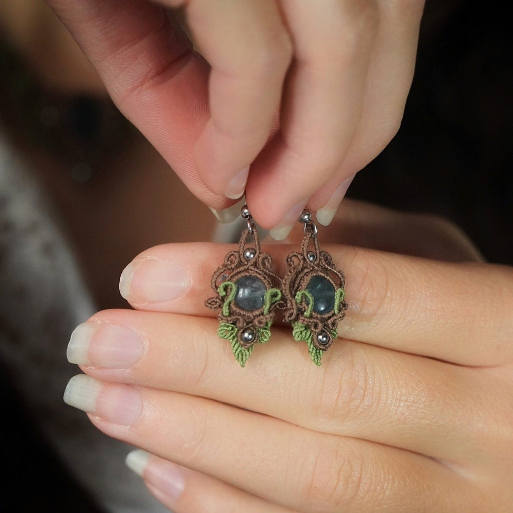 Boucles d’oreilles tenues dans une main - Coton et Astrance
