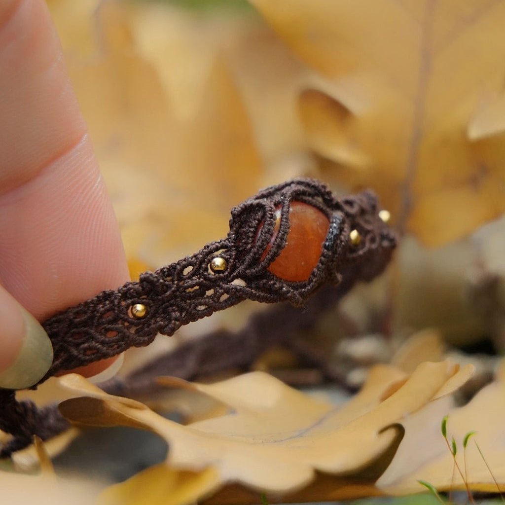 Détail du tissage fin en coton et perles dorées autour de la pierre de cornaline. Coton et Astrance