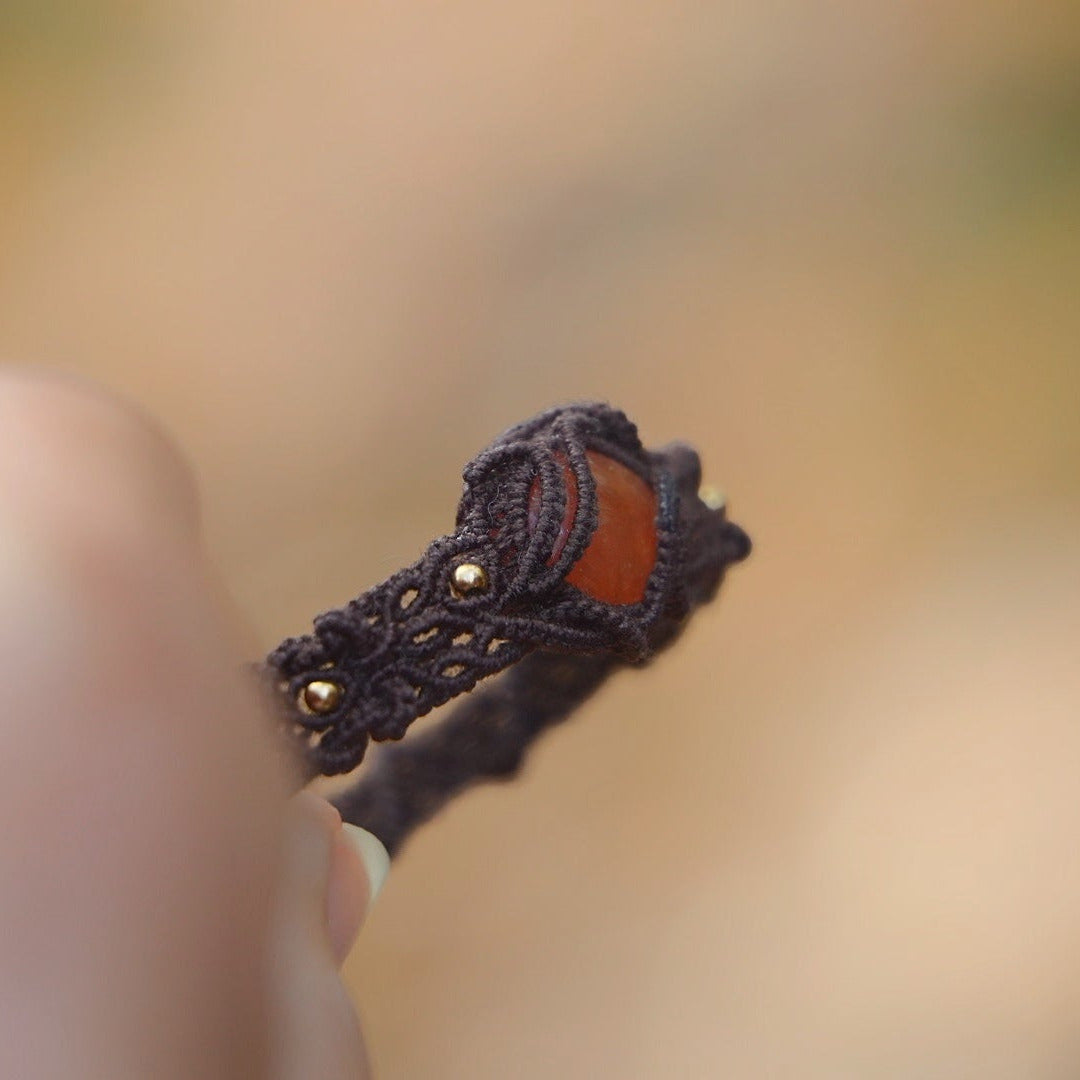 Gros plan sur la pierre cornaline orange ambrée et ses reflets au soleil. Coton et Astrance