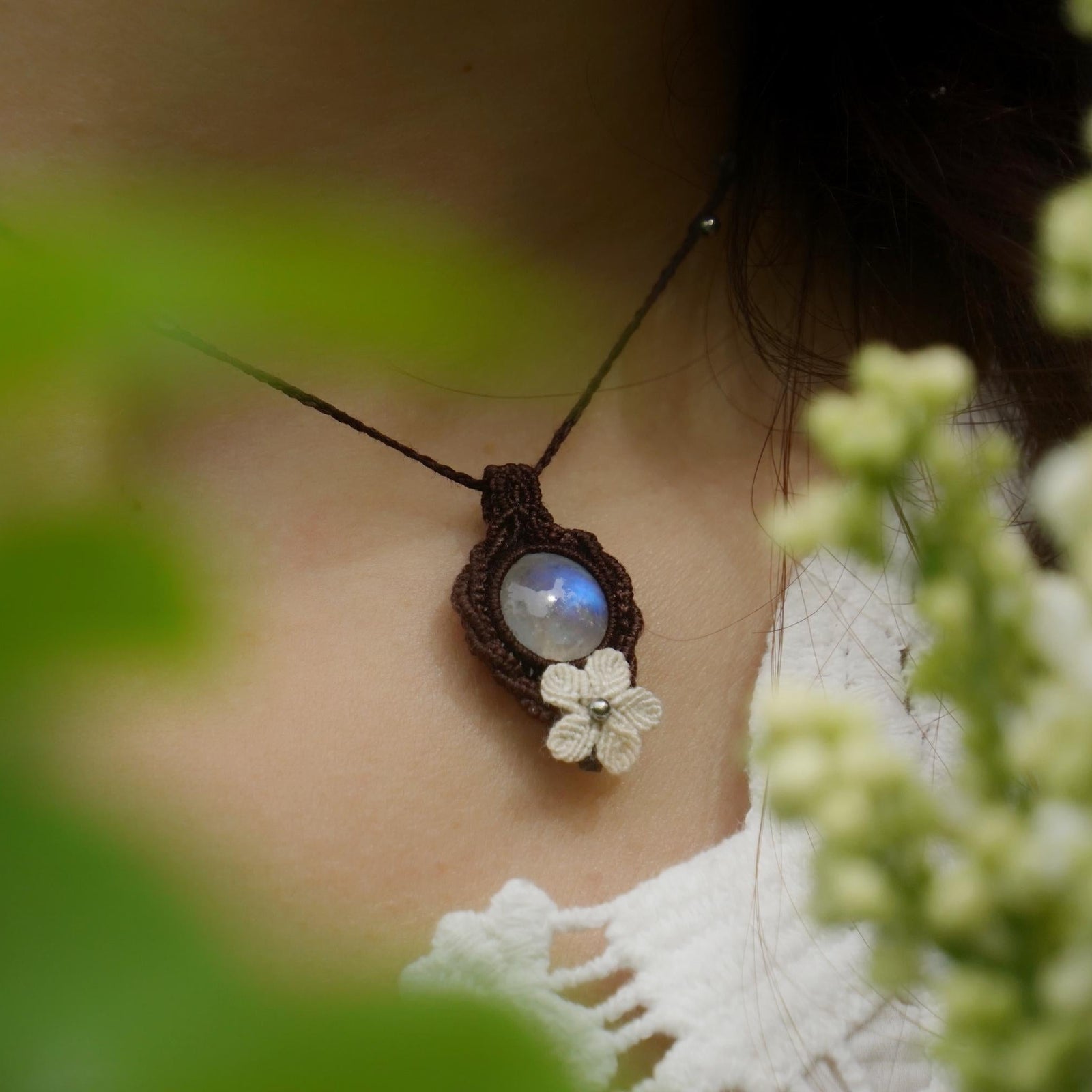 Collier elfique en labradorite blanche porté par un modèle à peau claire et cheveux bruns, vêtue d’habits féériques en dentelle blanche, bijou bohème artisanal réglable. Coton et Astrance