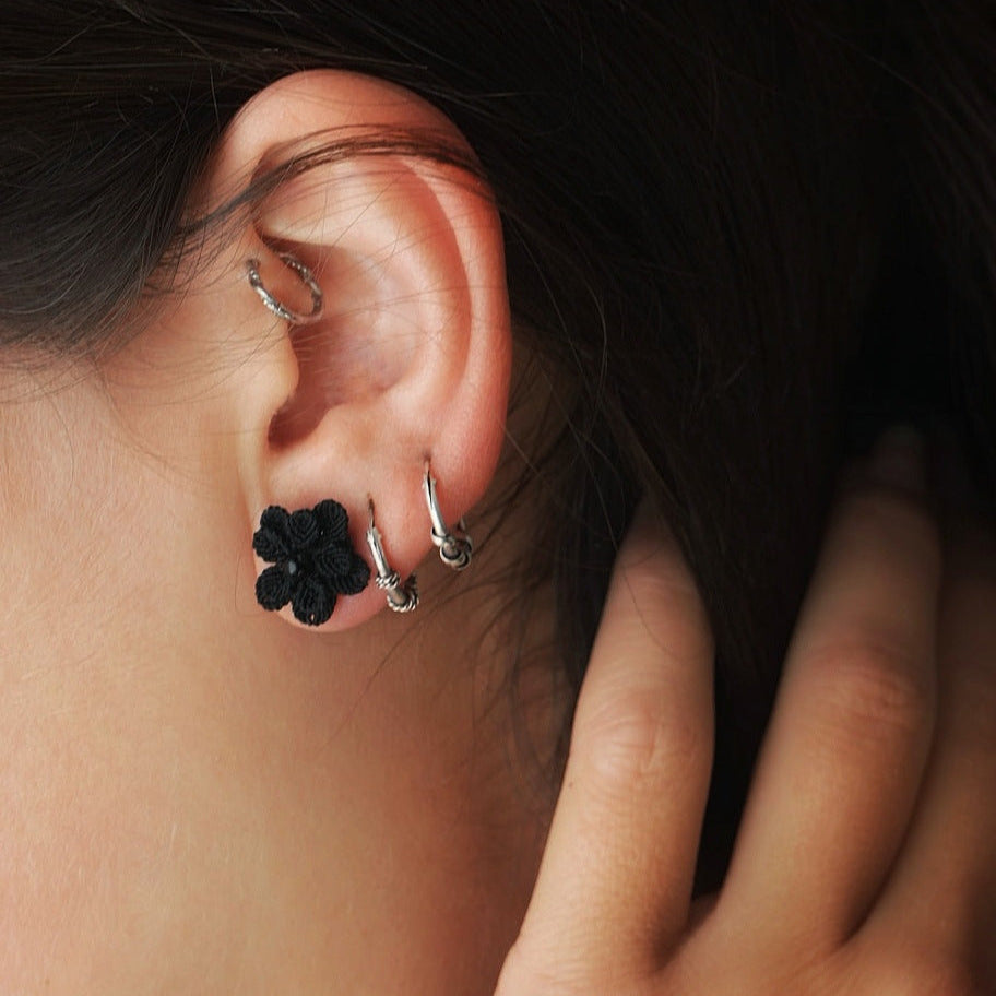 Boucles d’oreilles florales noires en onyx portées sur oreille féminine, bijou gothique artisanal en micro macramé. Coton et Astrance