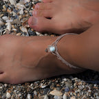 Duo de Bracelets de cheville bohème, ambiance plage et été sur les îles. Bijoux de pieds assortis. Micro macramé en fil de coton couleur lin beige avec une pierre de larimar bleu ciel accompagné d'une perle goutte argenté. Système de réglage à coulisse à l'arrière. Bijou porté sur une cheville dénudée à la peau caramel dans un univers sirène, marin avec plage de  coquillages