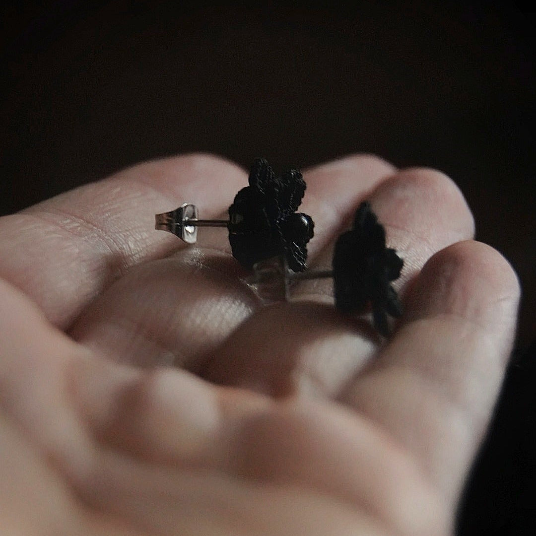 Boucles d’oreilles gothique florales noires tenues en main, bijou sombre elfique et élégant. Coton et Astrance