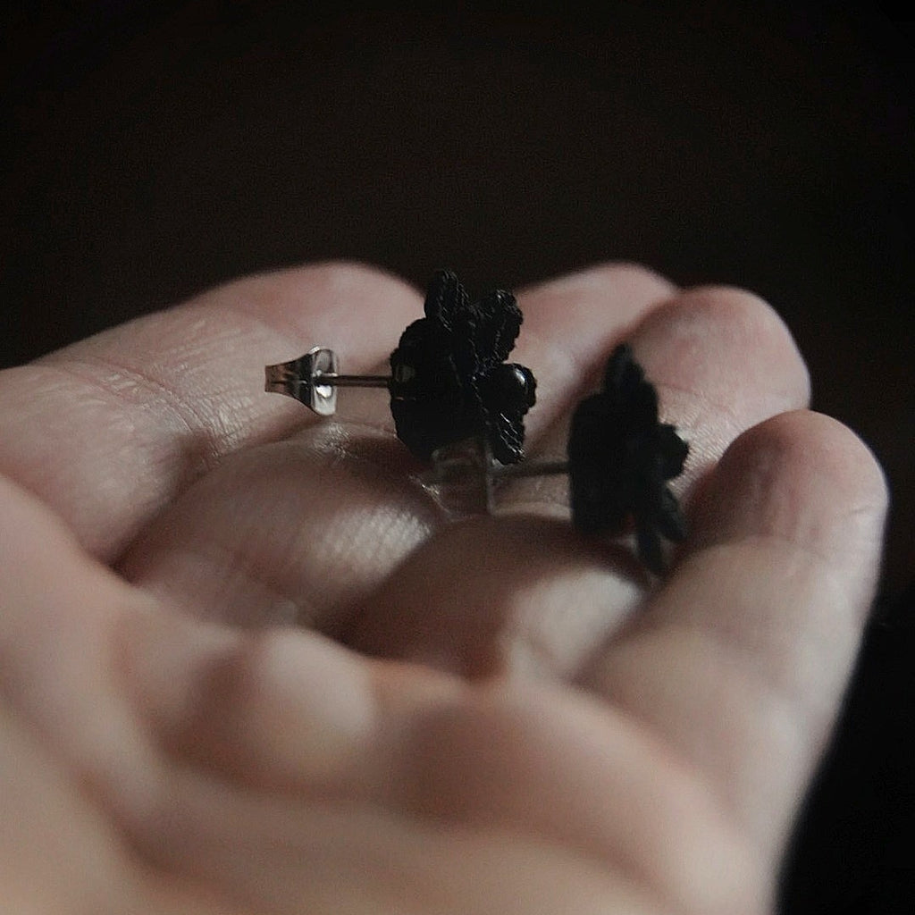Boucles d’oreilles gothique florales noires tenues en main, bijou sombre elfique et élégant. Coton et Astrance