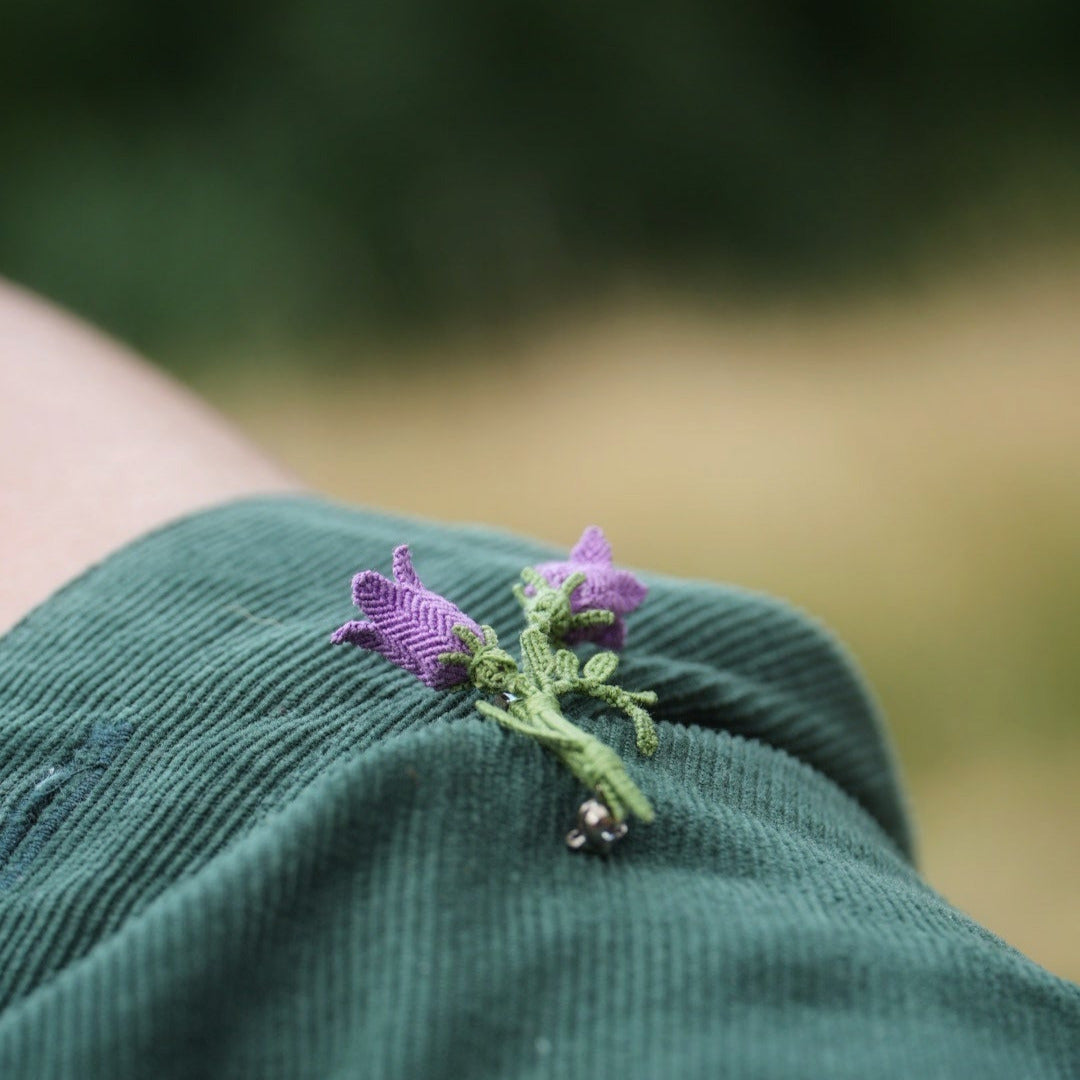 Bijou unisexe en micro macramé. Accessoire de mode inspiré de la nature et des fleurs sauvages d'été. Broche composée de deux campanules violettes avec feuille ciselée. Support de broche en laiton rhodié argenté fin avec cliquet de sécurité à tourner. Accessoire elfique, féérique pour veste, sac ou chapeau. Parfait en Boutonnière de mariage pour homme ou comme accessoires bohème pour costume et tenue de Festival. Bijou d'été poétique en 3D. Réalisé avec fil de coton de 0,3 mm vert tendre et violet. 