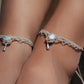 Duo de Bracelets de cheville bohème, ambiance plage et été sur les îles. Bijoux de pieds assortis. Micro macramé en fil de coton couleur lin beige avec une pierre de larimar bleu ciel accompagné d'une perle goutte argenté. Système de réglage à coulisse à l'arrière. Bijou porté sur une cheville dénudée à la peau caramel dans un univers sirène, marin avec bois flotté et sable fin.