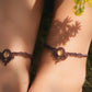 Bijoux de pieds, paire assortie de bracelets de chevilles à ambiance bohème celtique elfique. Fil marron foncé fin tissé en micro macramé avec entrelacs et arabesques, pierre centrale ovale petite taille jaune miel translucide. Bijoux hippie, bohème avec inspiration nature. Chevillères portées sur des chevilles à la peau pâle, bijoux de face avec jeu d'ombre et lumière et fleurs jaune en haut à droite.