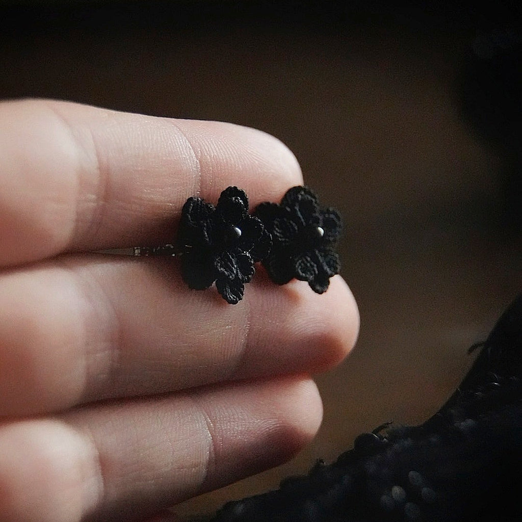 Boucles d’oreilles gothique florales noires tenues en main, bijou sombre elfique et élégant. Coton et Astrance
