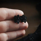 Boucles d’oreilles gothique florales noires tenues en main, bijou sombre elfique et élégant. Coton et Astrance