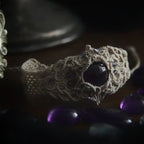 Bracelet large en macramé avec améthyste naturelle, bijou artisanal spirituel photographié dans un univers wicca gothique. Coton et Astrance