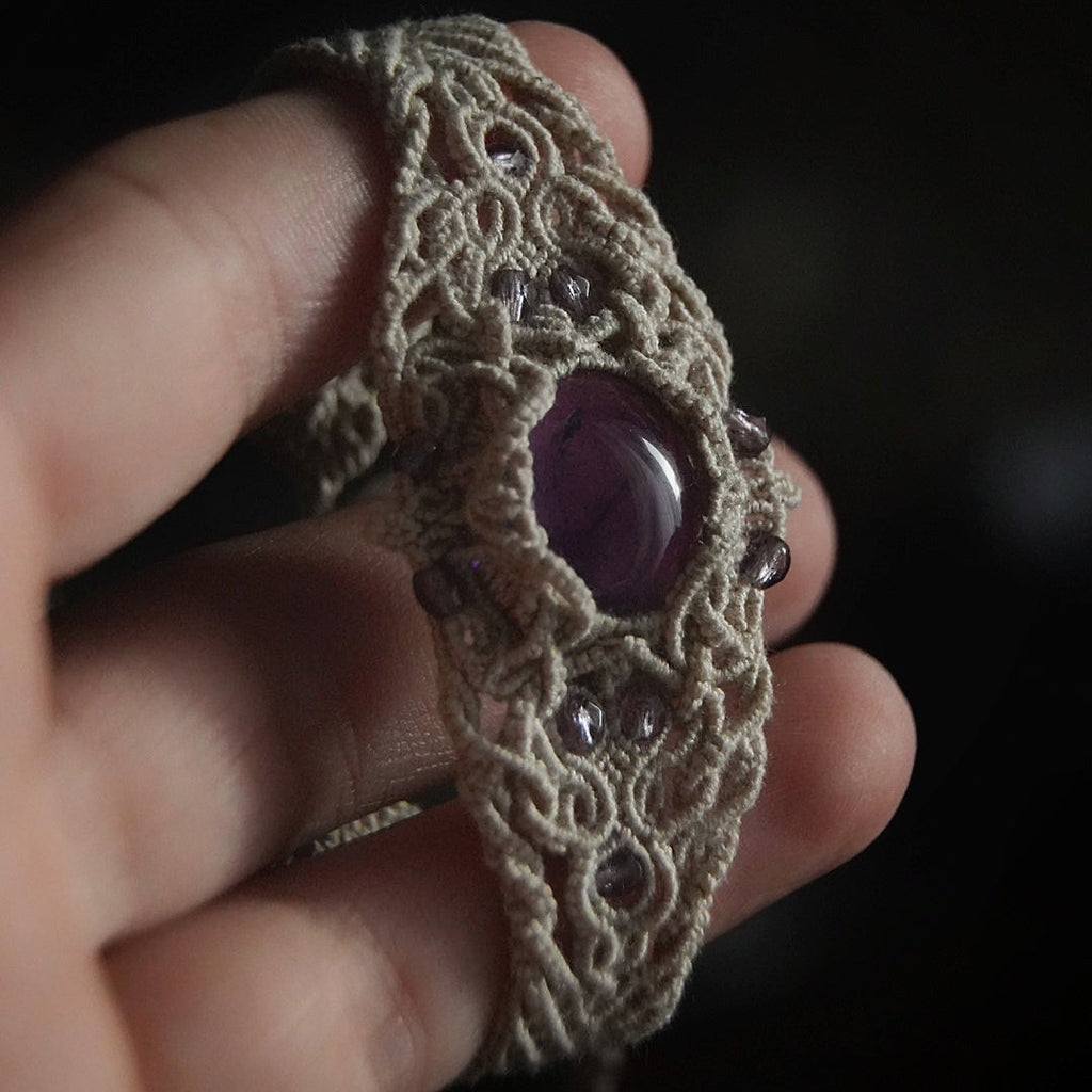 Bracelet manchette en améthyste violette, bijou wicca artisanal en micro macramé, porté avec dentelle noire dans une ambiance sorcière mystique. Coton et Astrance