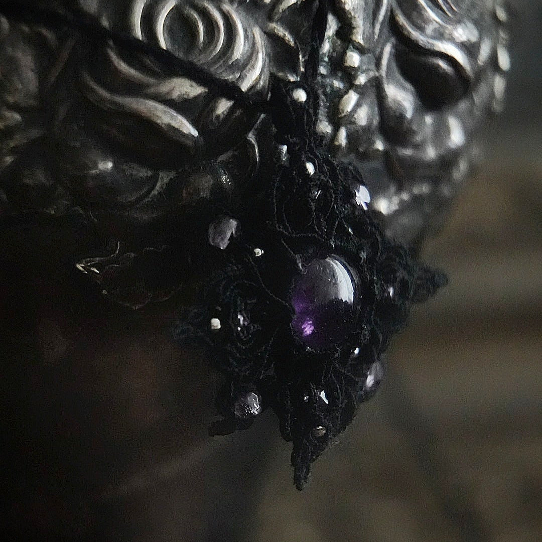 Bijou elfique sombre en micro macramé noir, pendentif étoile lumineux photographié sur fond gothique romantique. Coton et Astrance