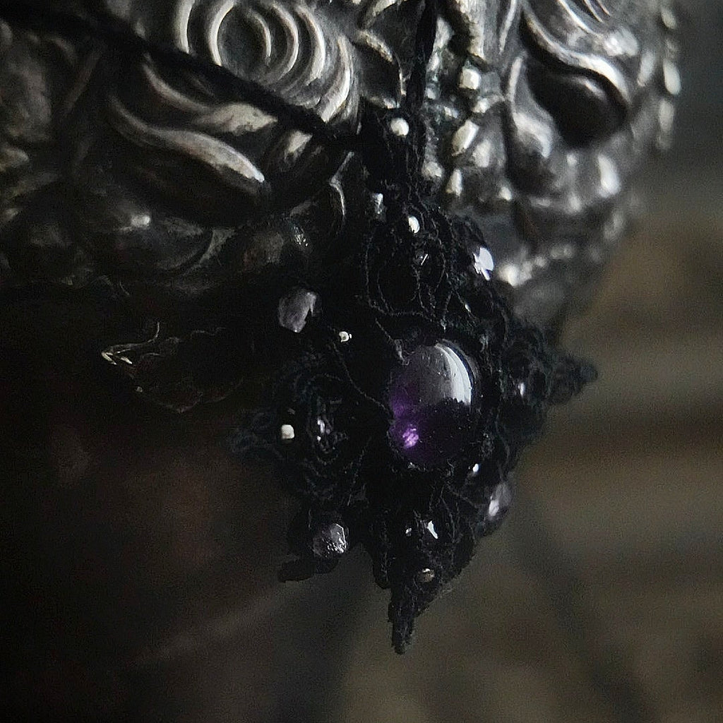 Bijou elfique sombre en micro macramé noir, pendentif étoile lumineux photographié sur fond gothique romantique. Coton et Astrance