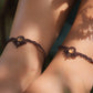 Bijoux de pieds, paire assortie de bracelets de chevilles à ambiance bohème celtique elfique. Fil marron foncé fin tissé en micro macramé avec entrelacs et arabesques, pierre centrale ovale petite taille jaune miel translucide. Bijoux hippie, bohème avec inspiration nature. Chevillères portées sur des chevilles à la peau pâle, bijoux de face avec jeu d'ombre et lumière et fleurs jaune en haut à droite.
