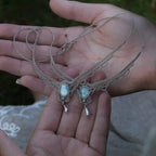 Duo de Bracelets de cheville bohème, ambiance plage et été sur les îles. Bijoux de pieds assortis. Micro macramé en fil de coton couleur lin beige avec une pierre de larimar bleu ciel accompagné d'une perle goutte argenté. Système de réglage à coulisse à l'arrière. Bijoux posé sur 2 mains dans un univers féérique bohème dans un jardin. Modèle avec Dreadlocks brunes, peau caramel et habits assorti au bijou de couleur lin naturel beige gris