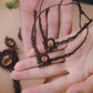 Bijoux de pieds, paire assortie de bracelets de chevilles à ambiance bohème celtique elfique. Fil marron foncé fin tissé en micro macramé avec entrelacs et arabesques, pierre centrale ovale petite taille jaune miel translucide. Bijoux hippie, bohème avec inspiration nature. Chevillères posée à plat dans 2 mains en coupe l'une au dessus de l'autre avec en fond d'autres bijoux dans les mêmes tons en citrine