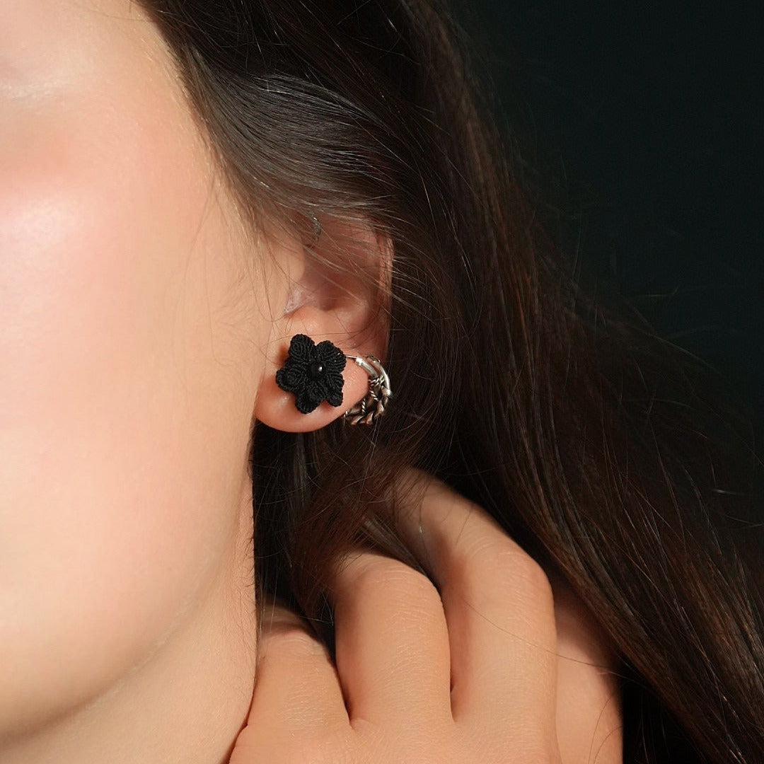 Boucles d’oreilles florales noires en onyx portées sur oreille féminine, bijou gothique artisanal en micro macramé. Coton et Astrance
