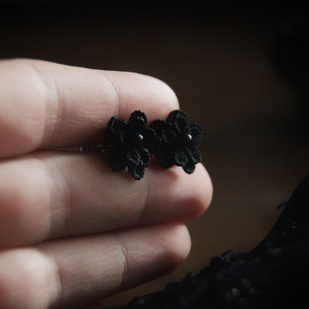 Boucles d’oreilles gothique florales noires tenues en main, bijou sombre elfique et élégant. Coton et Astrance