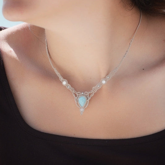 Collier ras-de-cou forme v Trésors d'Ecume composée d'une Larimar bleu ciel en poire pointe en bas, perles en nacre blanche ronde rappel des coquillages et de la plage, mini Perles rondes en acier inoxydable argenté pour le côté luxe et précieux. Fil de Coton couleur lin naturel (beige gris) de 0, 5 mm tissé en micro-macramé en relief version celtique. Collage 3 photos : Bijoux porté sur une femme bronzée et brune avec débardeur marron foncé. Photo ambiance tropiques et plages, style bohème hippie 
