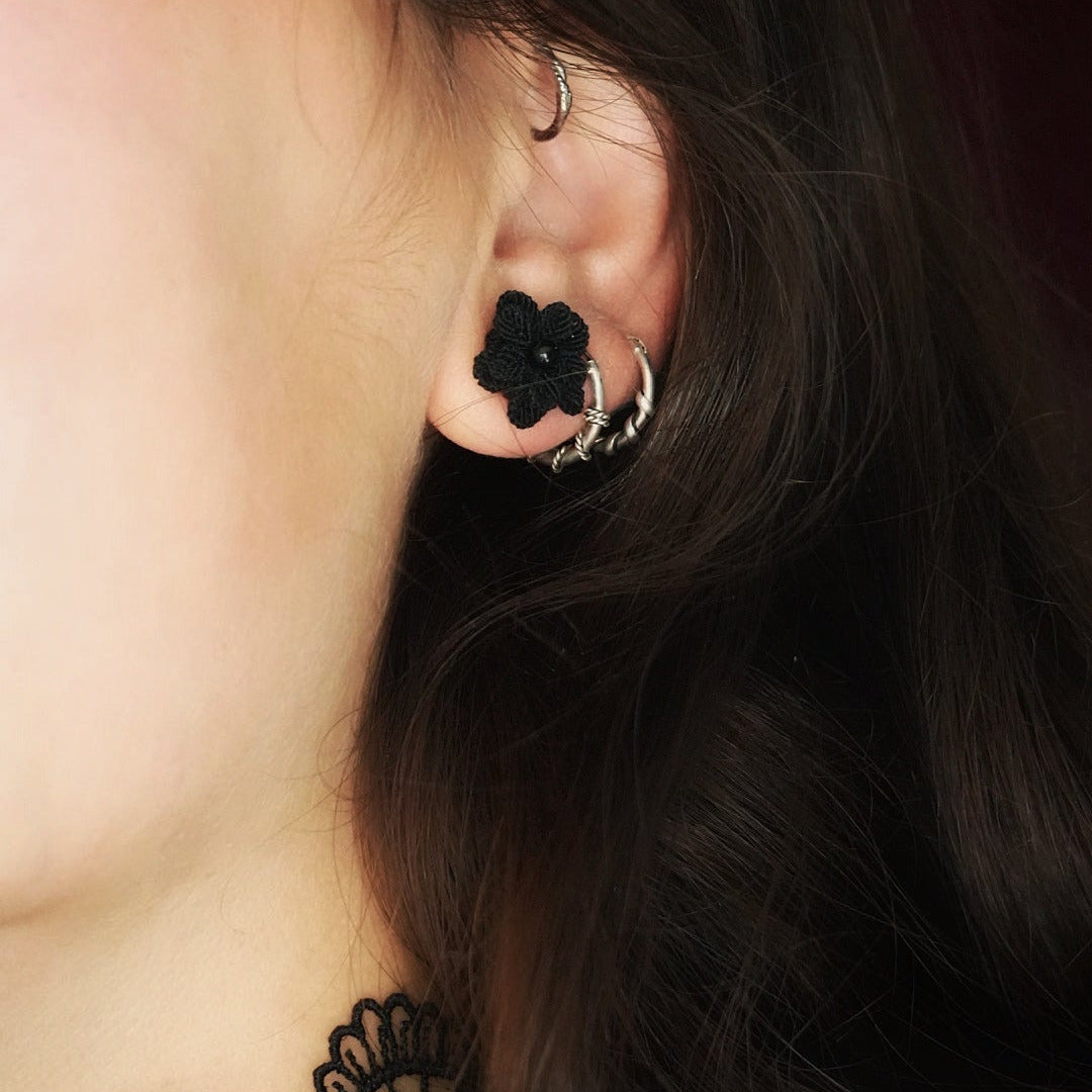 Boucles d’oreilles florales noires en onyx portées sur oreille féminine, bijou gothique artisanal en micro macramé. Coton et Astrance