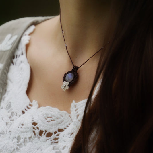 Collier elfique en labradorite blanche porté par un modèle à peau claire et cheveux bruns, vêtue d’habits féériques en dentelle blanche, bijou bohème artisanal réglable. Coton et Astrane