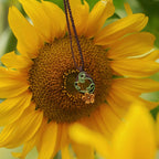 Collier elfique floral en citrine et macramé, fait main en France. Pièce artisanale réglable de la collection Clairière de Miel, photographiée au cœur de la nature au centre d'une fleur de tournesol pour souligner son inspiration bohème et féérique.