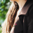 Broche florale rouge en micro macramé avec cœur doré, accessoire artisanal bohème et elfique, épinglée sur veste en laine marron foncé.