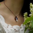 Collier elfique en labradorite blanche porté par un modèle à peau claire et cheveux bruns, vêtue d’habits féériques en dentelle blanche, bijou bohème artisanal réglable. Coton et Astrance