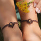 Bijoux de pieds, paire assortie de bracelets de chevilles à ambiance bohème celtique elfique. Fil marron foncé fin tissé en micro macramé avec entrelacs et arabesques, pierre centrale ovale petite taille jaune miel translucide. Bijoux hippie, bohème avec inspiration nature. Chevillères portées sur des chevilles à la peau pâle, bijoux de face avec jeu d'ombre et lumière et fleurs jaune en haut à droite.