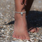 Duo de Bracelets de cheville bohème, ambiance plage et été sur les îles. Bijoux de pieds assortis. Micro macramé en fil de coton couleur lin beige avec une pierre de larimar bleu ciel accompagné d'une perle goutte argenté. Système de réglage à coulisse à l'arrière. Bijou porté sur une cheville dénudée à la peau caramel dans un univers sirène, marin avec bois flotté et sable fin.