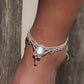 Duo de Bracelets de cheville bohème, ambiance plage et été sur les îles. Bijoux de pieds assortis. Micro macramé en fil de coton couleur lin beige avec une pierre de larimar bleu ciel accompagné d'une perle goutte argenté. Système de réglage à coulisse à l'arrière. Bijou porté sur une cheville dénudée à la peau caramel dans un univers sirène, marin avec bois flotté et sable fin.