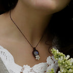 Collier elfique en labradorite blanche porté par un modèle à peau claire et cheveux bruns, vêtue d’habits féériques en dentelle blanche, bijou bohème artisanal réglable. Coton et Astrance